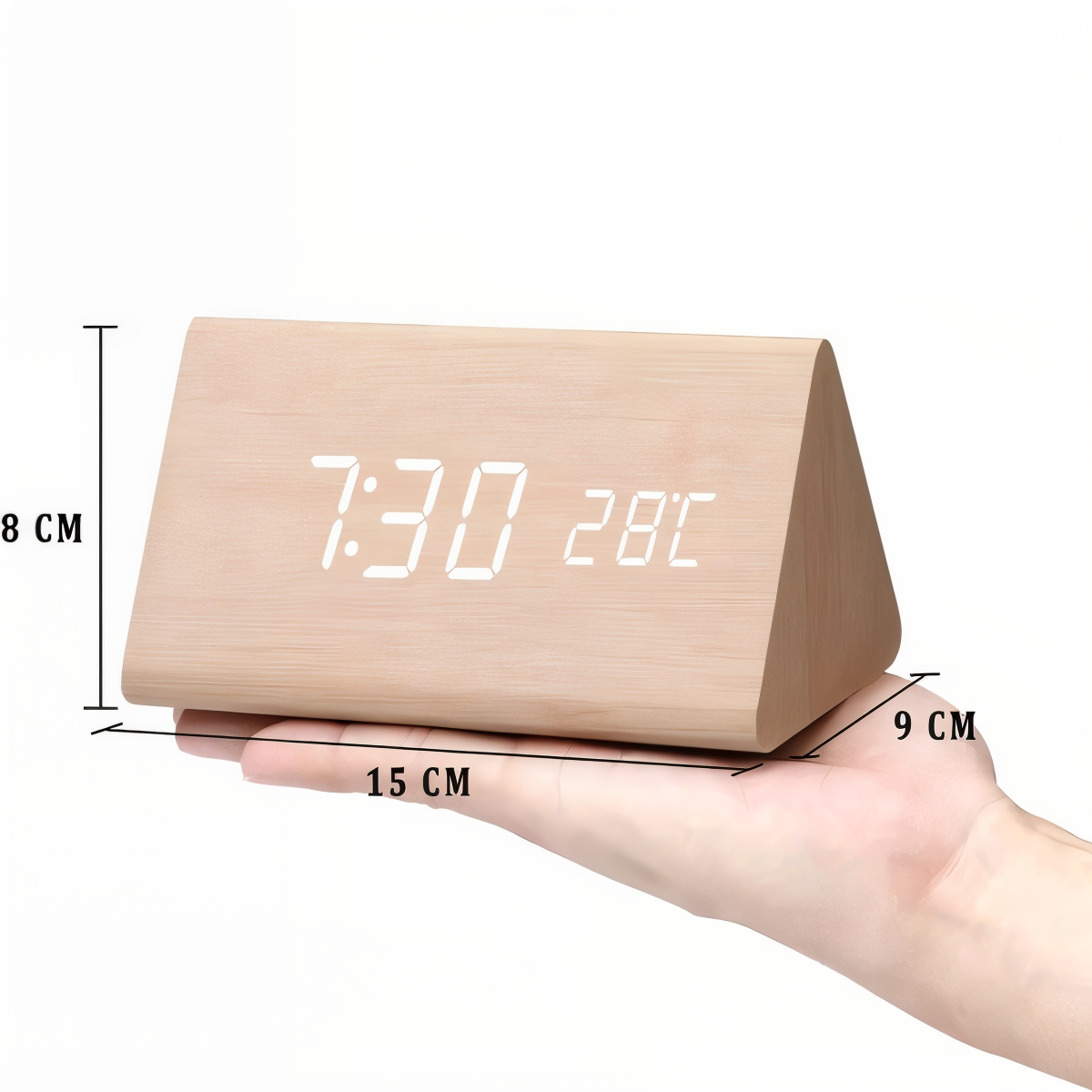 Hand holding a triangular light-wood digital LED alarm clock showing time and temperature with dimension labels.