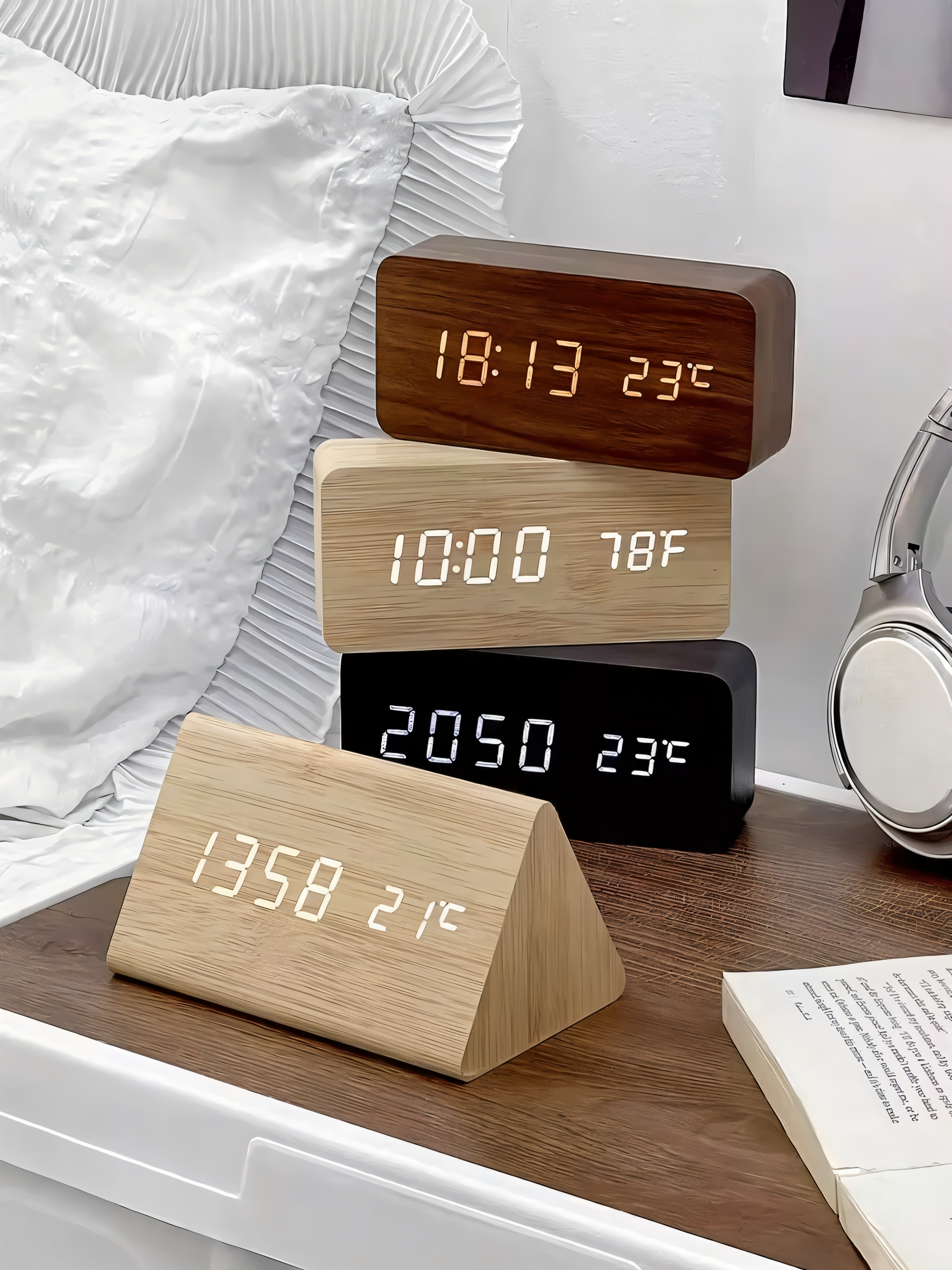 Four modern LED digital alarm clocks in wood-grain and black finishes showing time and temperature on a bedside table.