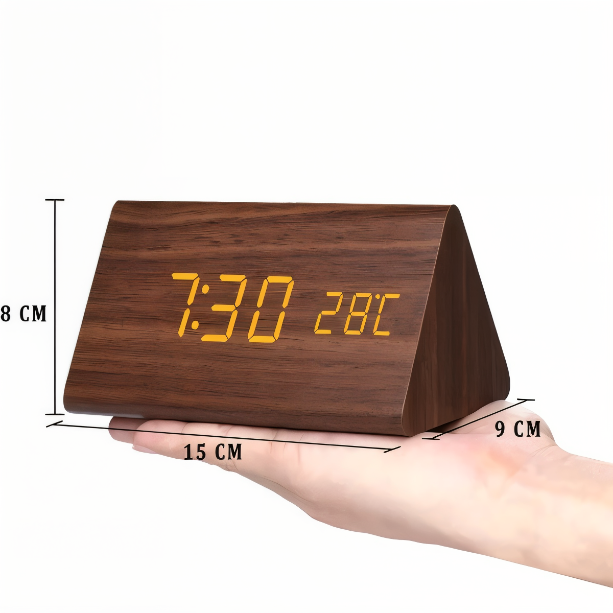 Triangle wooden LED alarm clock showing 7:30 and 28°C on a palm, with 15x8x9 cm dimensions labeled.