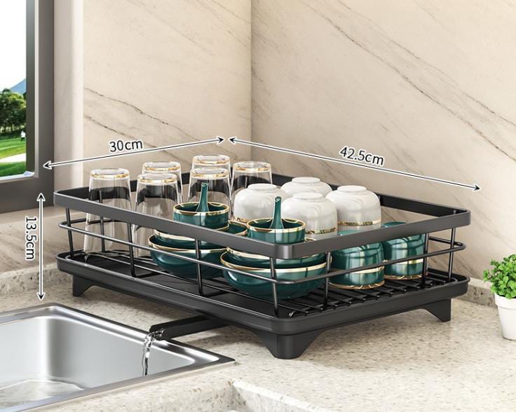 Black Fitlybuy adjustable dish drying rack with integrated drainer, holding cups and bowls by a kitchen sink.