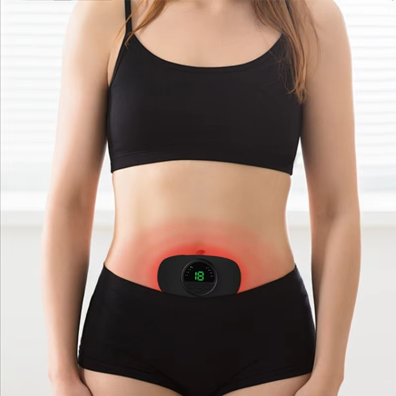 Woman wearing a black wireless Fitlybuy TENS device on her abdomen with a glowing red light for period pain relief.