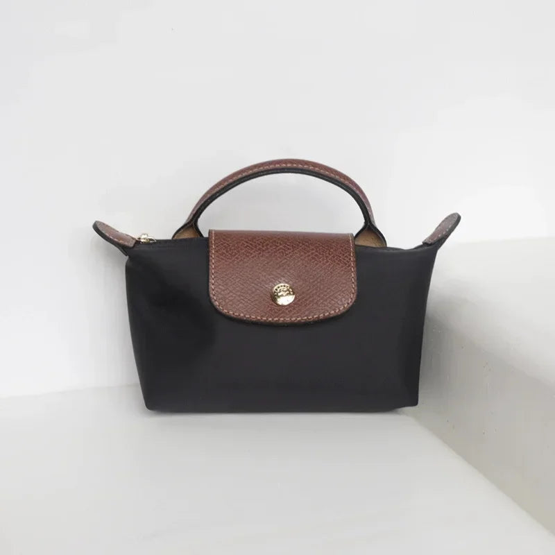 Fitlybuy Calo mini black handbag with a brown leather top flap, gold snap, and arched handle on a white surface.