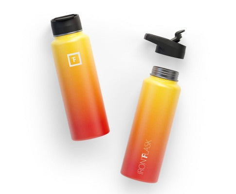 Two yellow-to-red gradient Iron Flask water bottles, one capped and one with its lid off, on a white background.