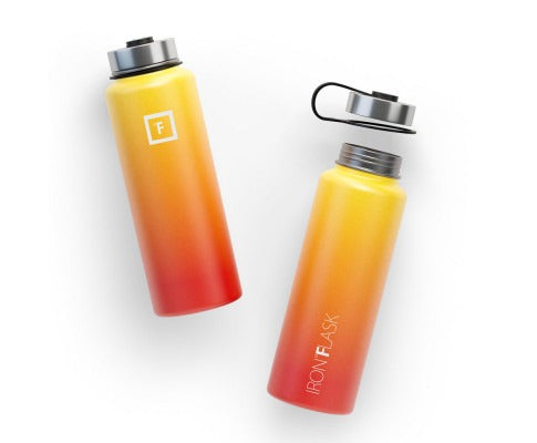 Two yellow-to-red gradient Iron Flask water bottles, one capped and one open, on a plain white background.