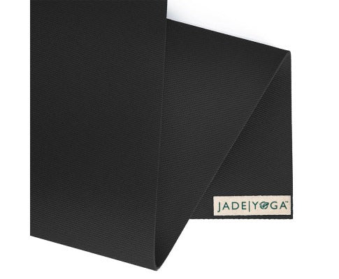 Close-up of a black textured Jade Yoga mat with EcoGrip technology, folded to reveal the brand label on a white tab.
