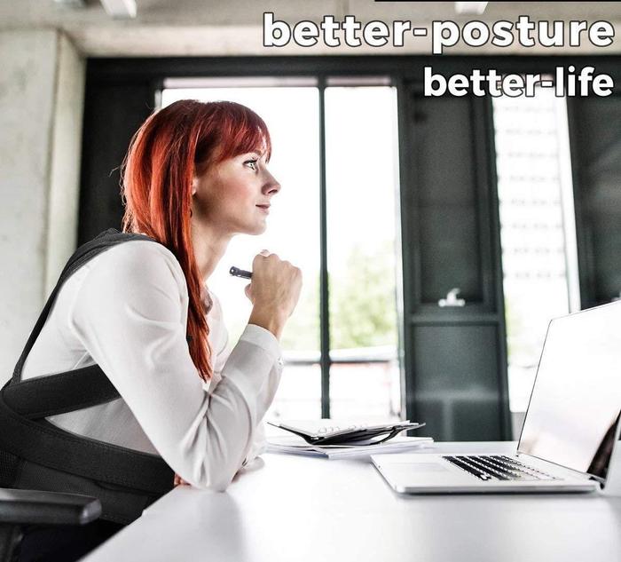 Woman wearing a black Fitlybuy Posture Corrector Pro for ergonomic back support while working at a desk with a laptop.