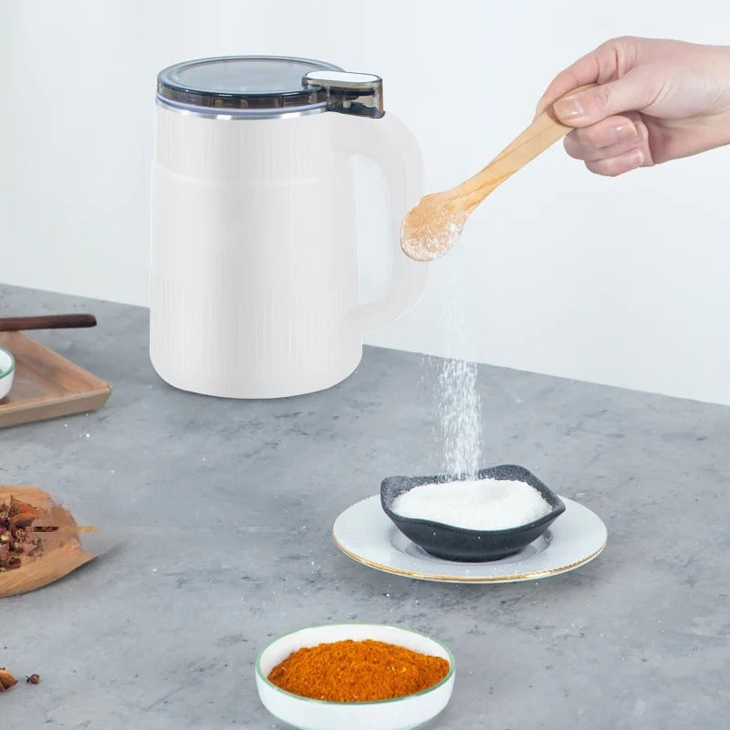 Fitlybuy white electric grain mill on a grey surface, with a hand pouring ground powder into a small bowl with a spoon.