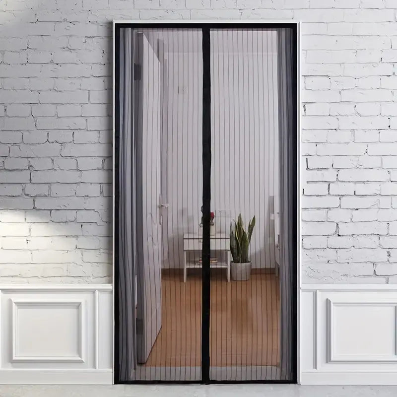 Black Fitlybuy BugGuard magnetic mesh fly screen door installed on a white door frame against a white brick wall.