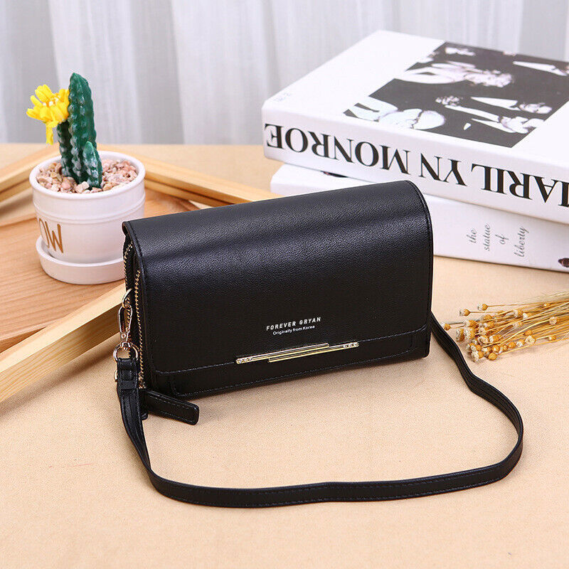 Elegant black leather Fitlybuy crossbody bag with gold accent, sitting on a table next to a small cactus and books.