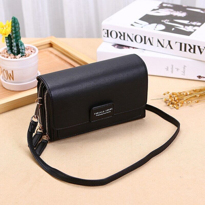 Black Fitlybuy leather crossbody bag with a flap closure, gold zippers, and strap, sitting on a wooden table.
