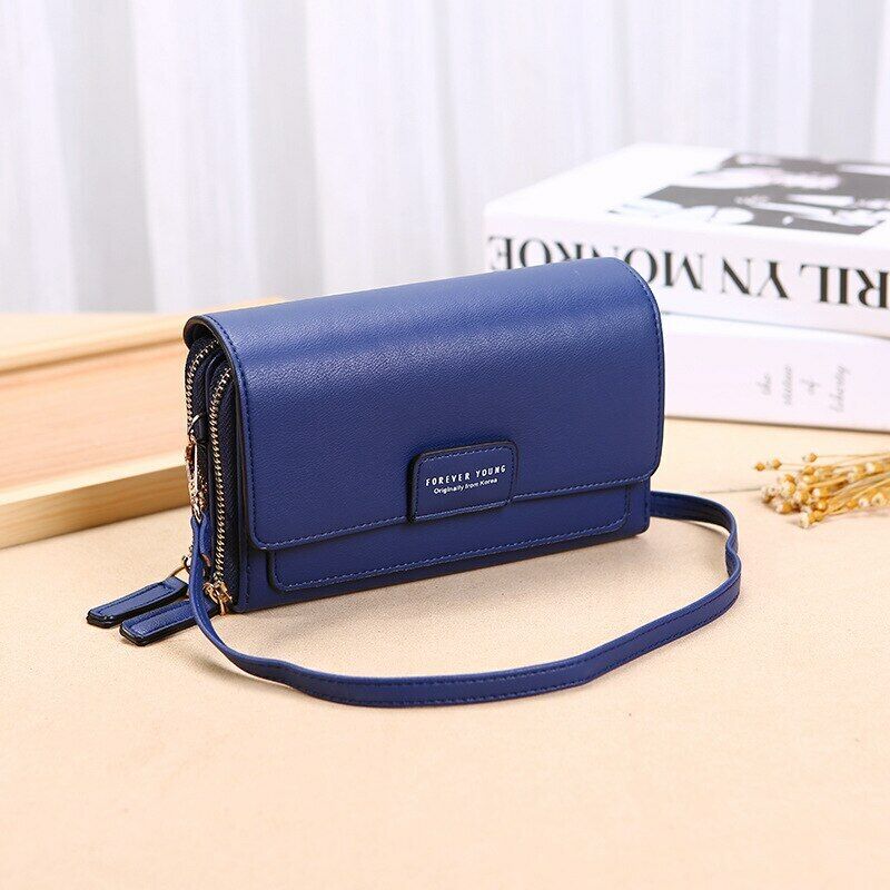 Fitlybuy blue leather crossbody bag with a flap closure, gold zippers, and a slim strap on a table.