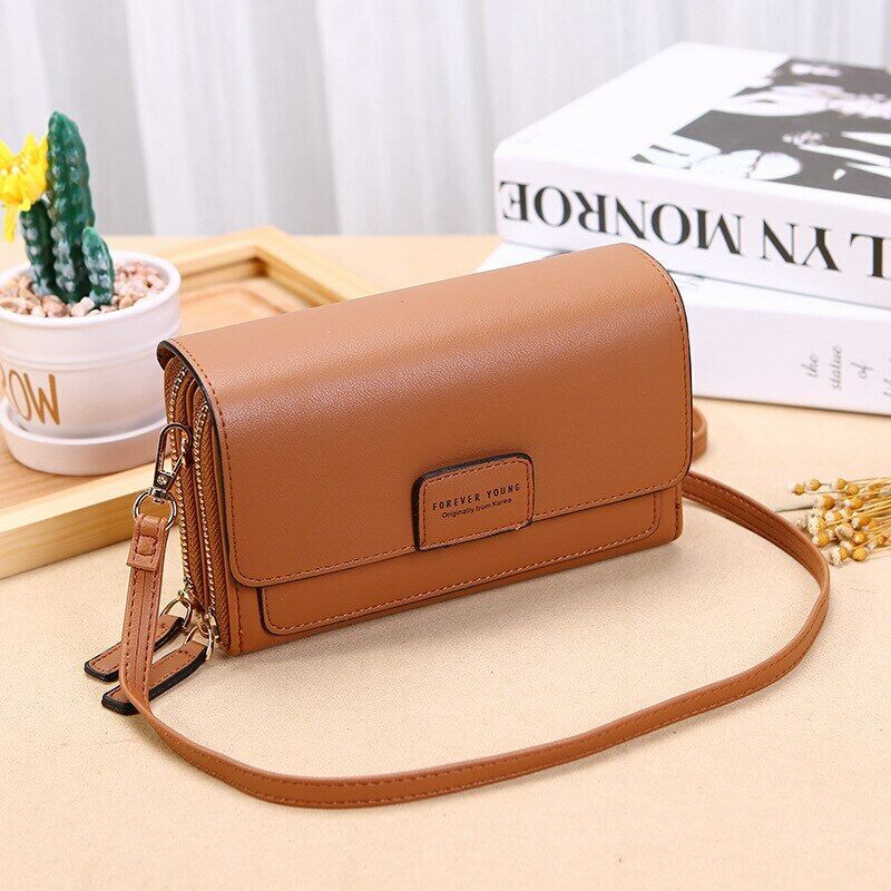 Tan Fitlybuy leather crossbody bag with a flap closure, zipper compartments, and a thin shoulder strap on a table.