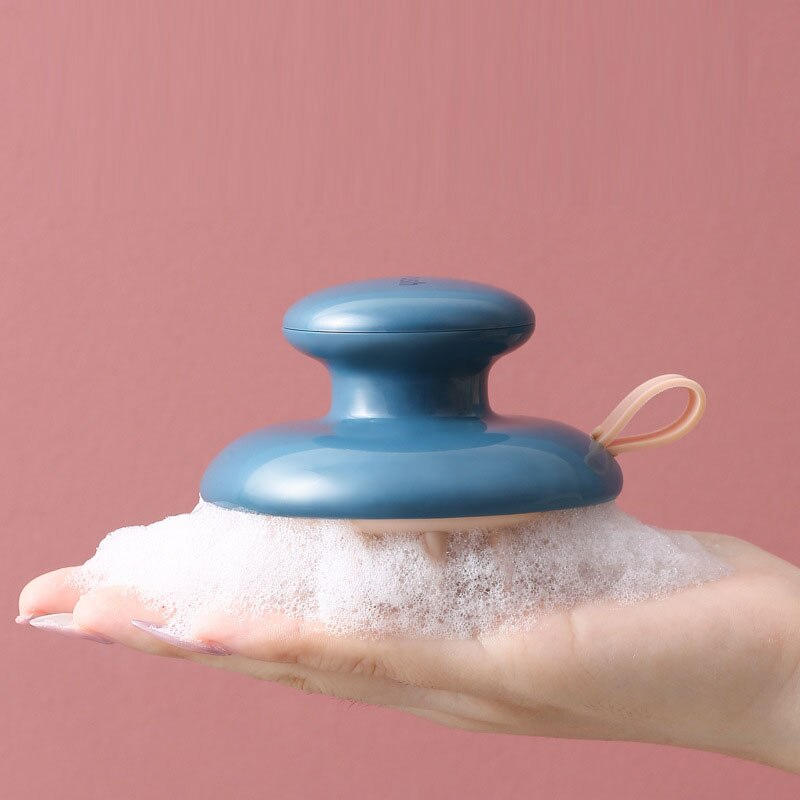 Blue Fitlybuy Scalp Bliss Pro massager with ergonomic grip and sudsy bristles in a palm against a pink background.