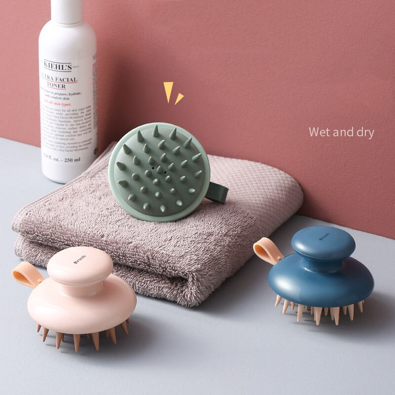 Fitlybuy Scalp Bliss Pro massagers in sage, blue, and pink with ergonomic grips on a towel, next to a toner bottle.