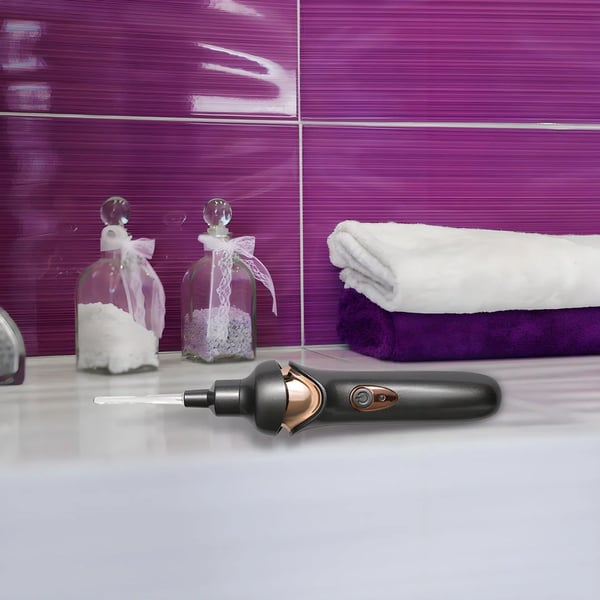 Fitlybuy gray and rose gold electric ear wax removal tool on a bathroom counter next to towels.
