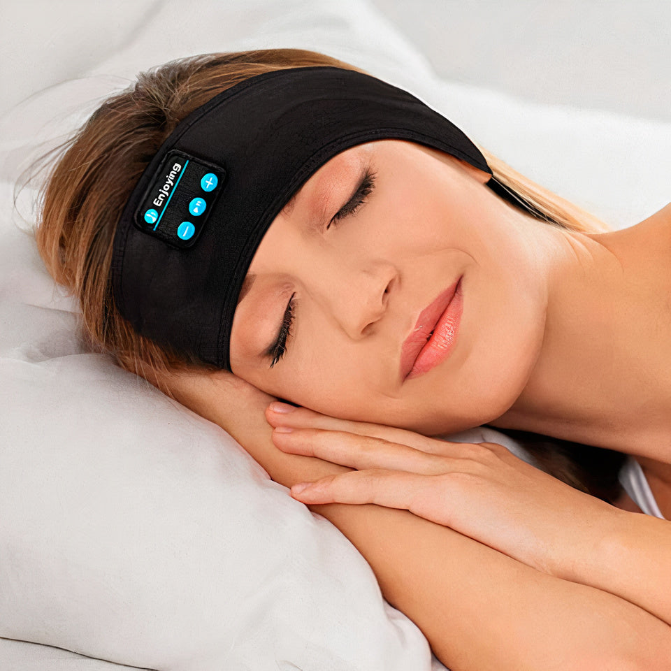 A woman sleeps wearing a black Fitlybuy Bluetooth headband with integrated audio controls on a white pillow.