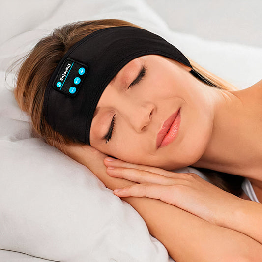 A woman sleeps wearing a black Fitlybuy Bluetooth headband with integrated audio controls on a white pillow.