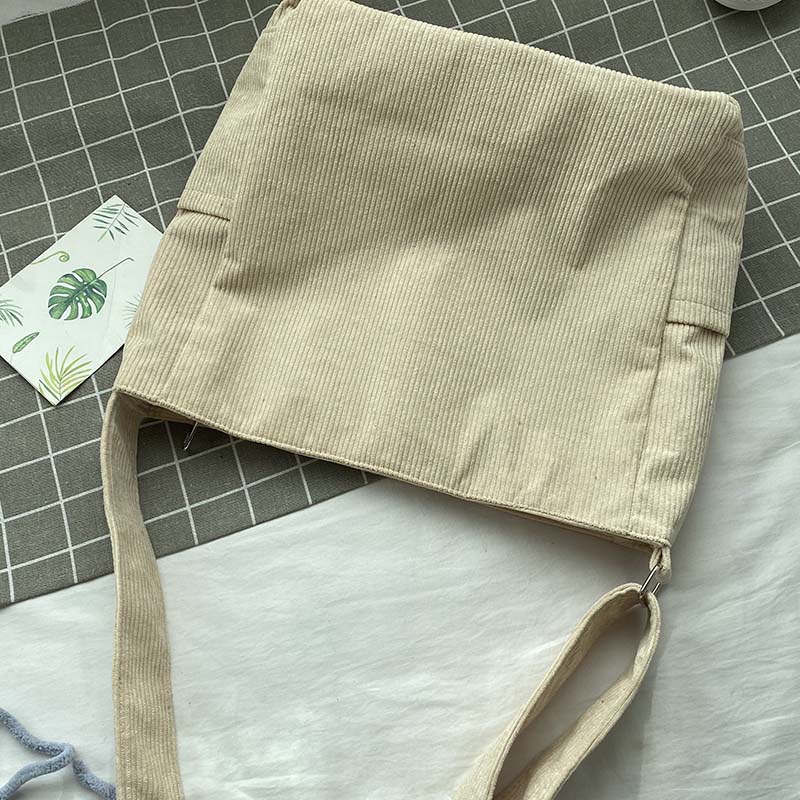 Beige corduroy Fitlybuy crossbody bag with an adjustable strap, displayed on a checkered background with a leaf card.