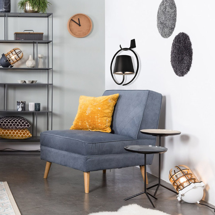 Fitlybuy LumiCord black wireless LED hanging lamp mounted on a modern living room wall above a blue armchair.