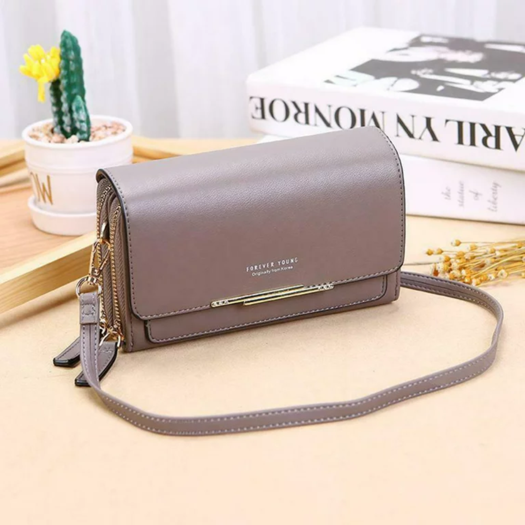 Taupe leather Fitlybuy crossbody bag with gold hardware, zippered compartments, and strap, set on a wooden desk.