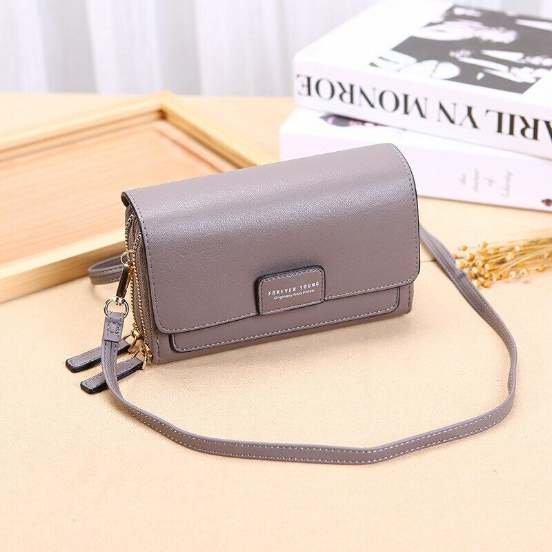 Fitlybuy grey premium leather crossbody bag with dual-zipper compartments on a table with books.