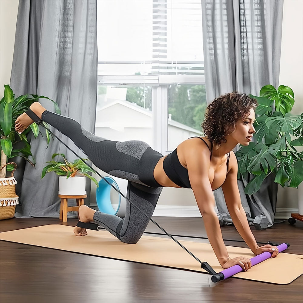 A woman uses a purple Fitlybuy Pilates bar with resistance bands on a yoga mat in a home studio.