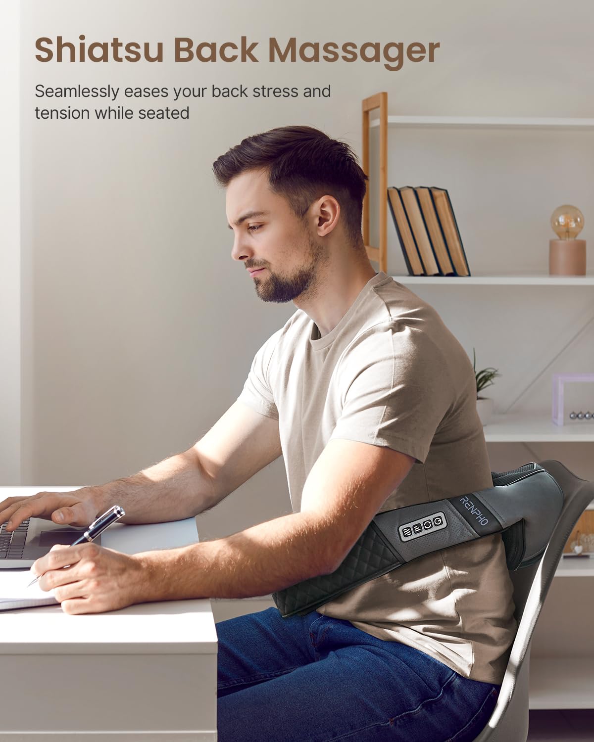 Man wearing a gray, U-shaped heated neck and shoulder massager while working at a desk.