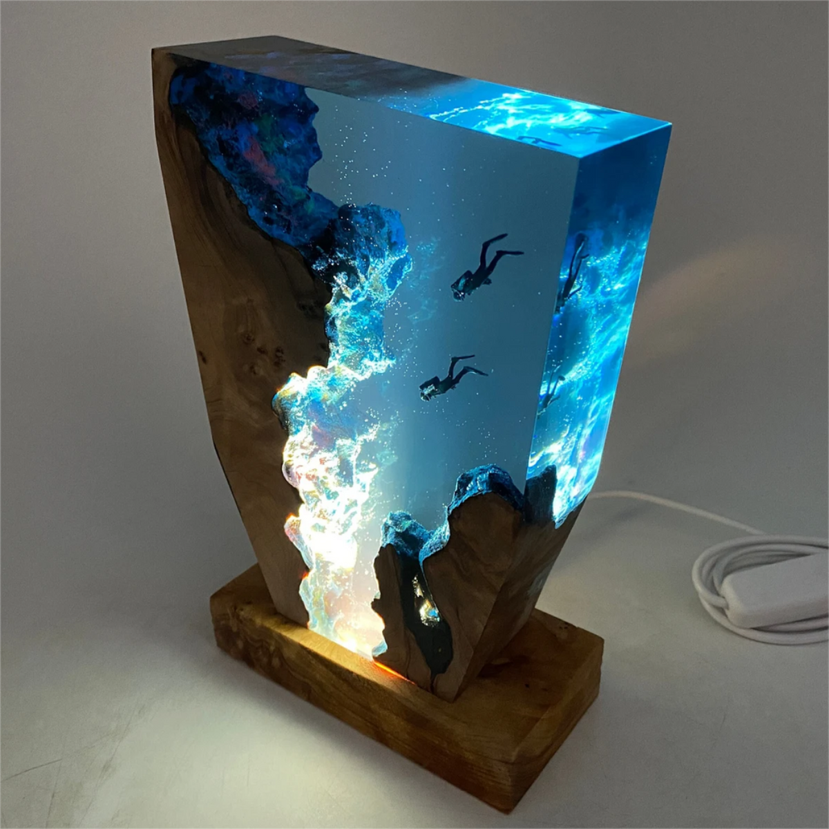 Handmade epoxy ocean-themed lamp featuring wood, glowing blue water, and scuba diver figurines on a wooden base.