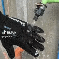 Black Fitlybuy waterproof heated adventure gloves being tested under running water to demonstrate water resistance.