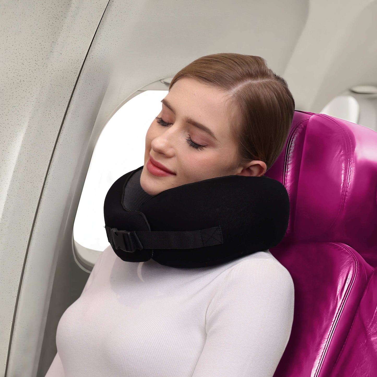 Woman wearing a black, ergonomic Fitlybuy butterfly travel neck pillow with adjustable strap on a plane.