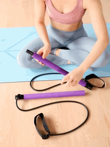Person assembling a purple Fitlybuy Pilates bar with black resistance bands on a blue mat.