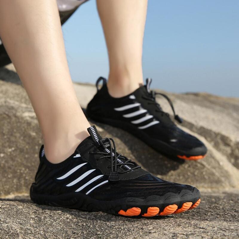 Person wearing black Fitlybuy barefoot shoes with white stripes and orange non-slip grip soles on rocky terrain.