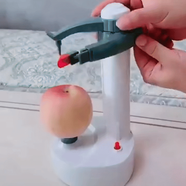 Fitlybuy electric peeler with white base and gray arm peeling a fresh apple. A hand positions the blade for precision.