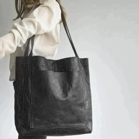 Fitlybuy Eva black leather tote bag with an elegant, spacious design, worn over the shoulder by a woman.