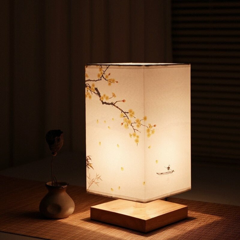 Fitlybuy Kyomi bamboo table lamp with cream shade, floral art, and wooden base, set on a table in a dimly lit room.