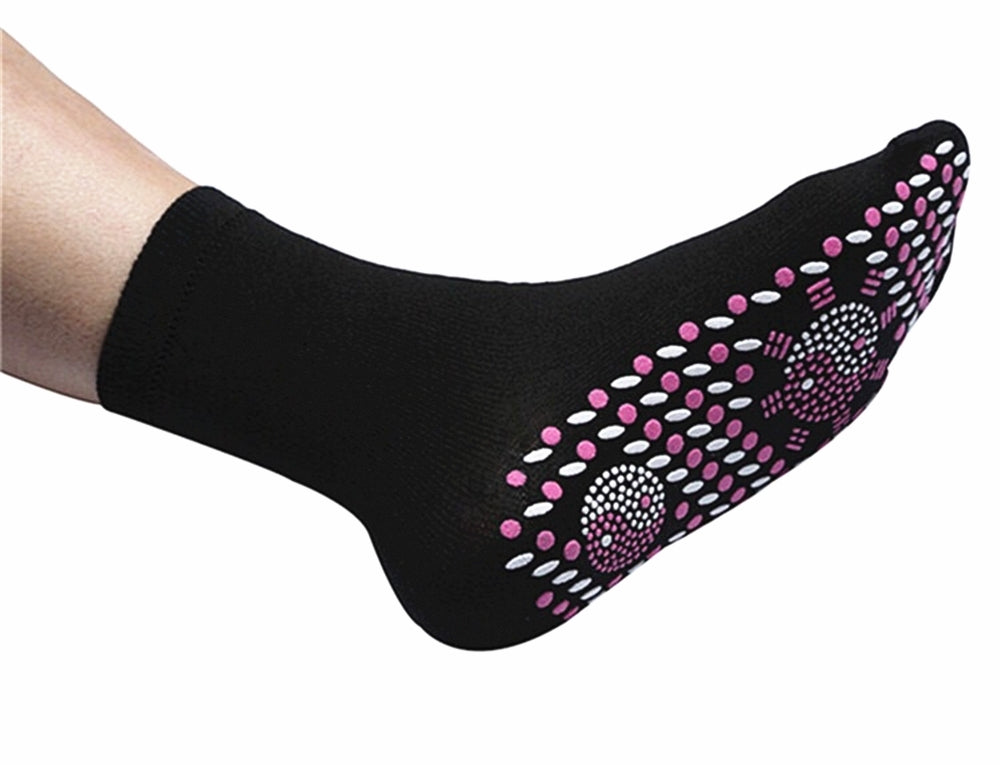 Black Fitlybuy self-heating magnetic sock with pink and white acupressure dots on the sole worn on a foot.