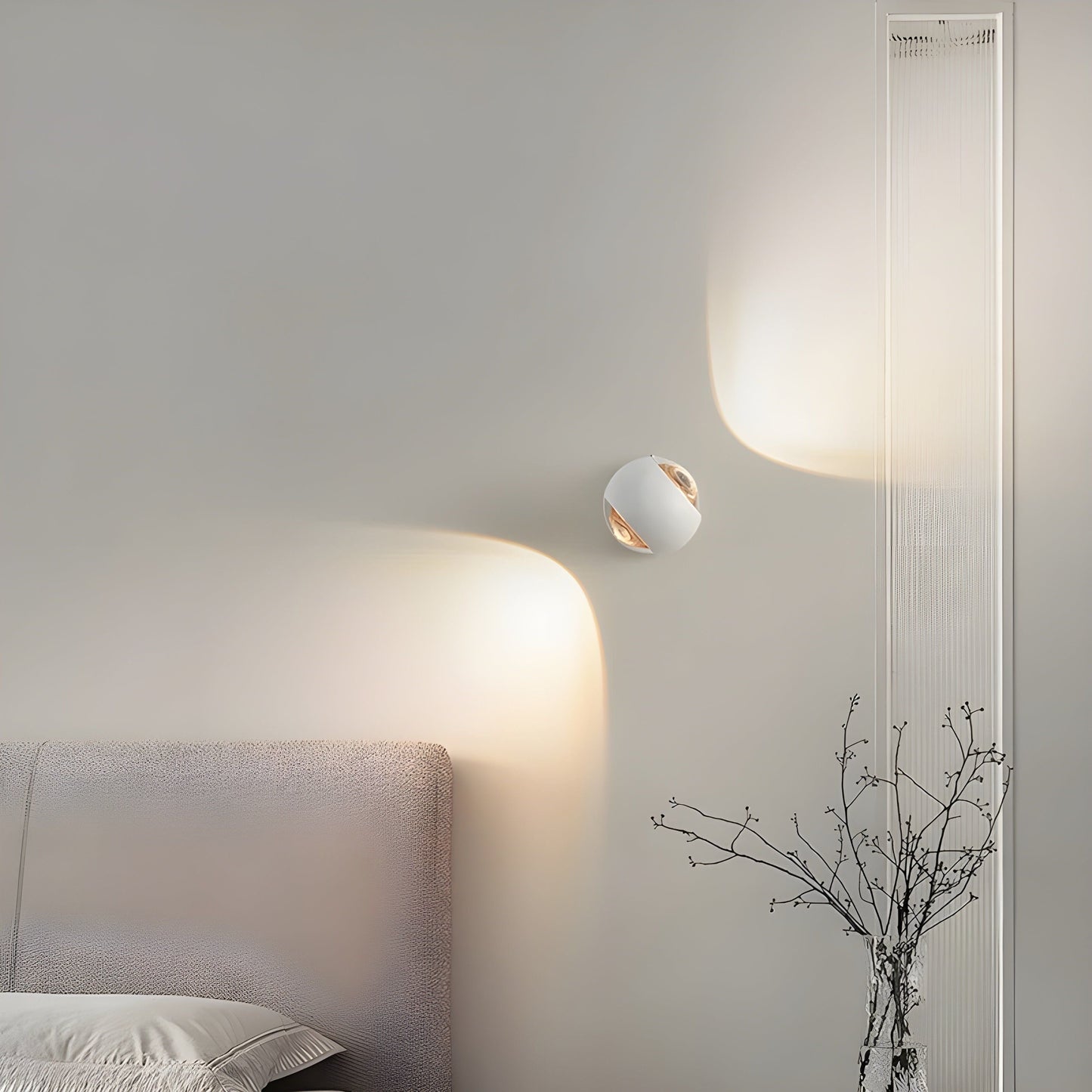 Fitlybuy ModernEdge white rotating wall light casting a soft, warm LED glow on a bedroom wall near a bed.