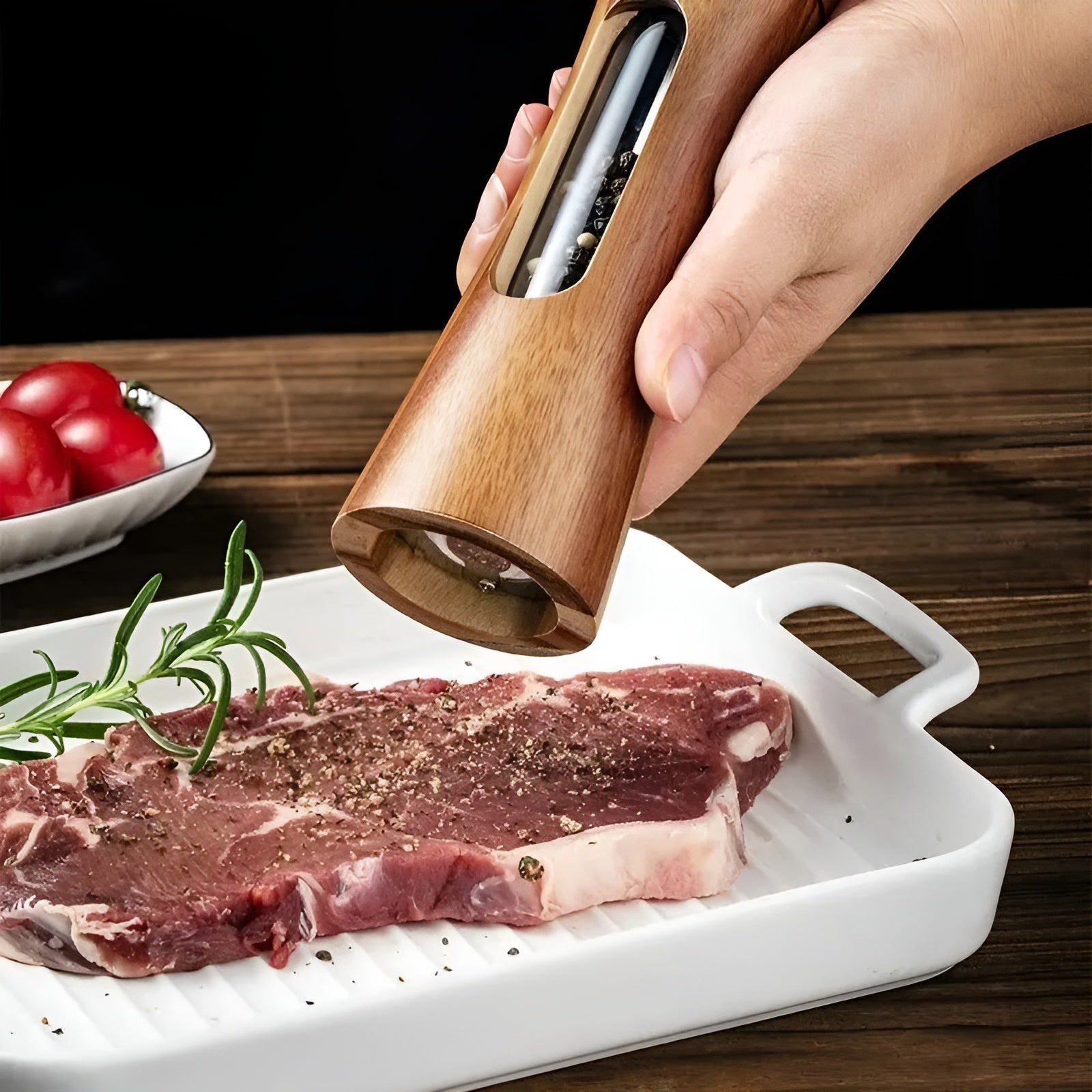 Hand seasoning raw steak with an elegant Fitlybuy wooden manual salt and pepper mill with a clear spice window.