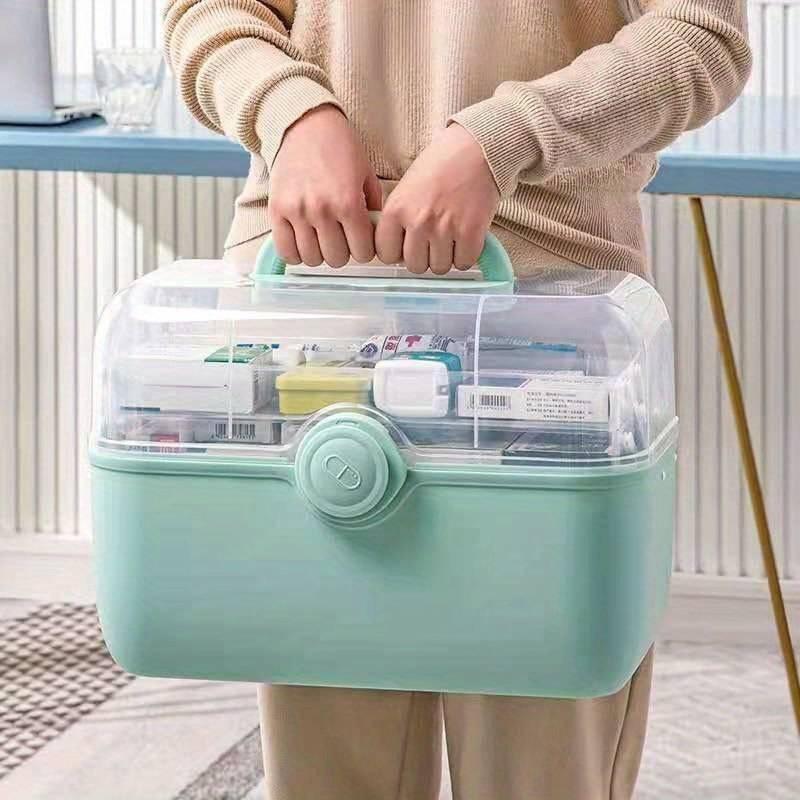 Person holding a mint green Fitlybuy MediSmart pill organizer with a clear, tiered lid for medicine storage.
