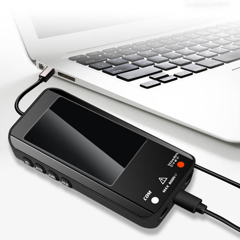 Fitlybuy smart digital multimeter, black rectangular device with side buttons, charging near a laptop.
