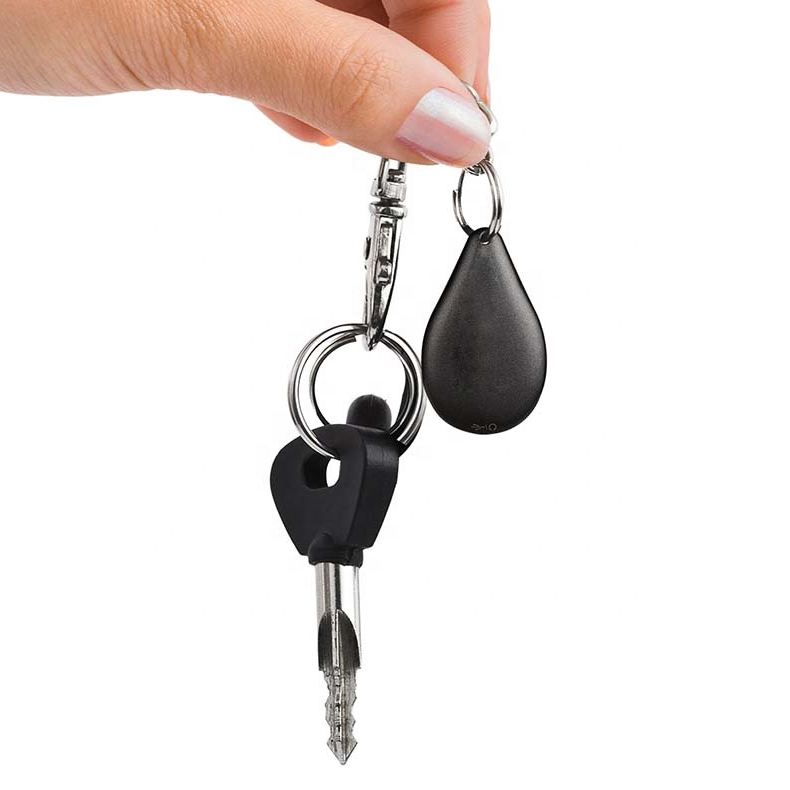Hand holds a black, teardrop-shaped Fitlybuy keychain voice recorder alongside a metal key on a white background.