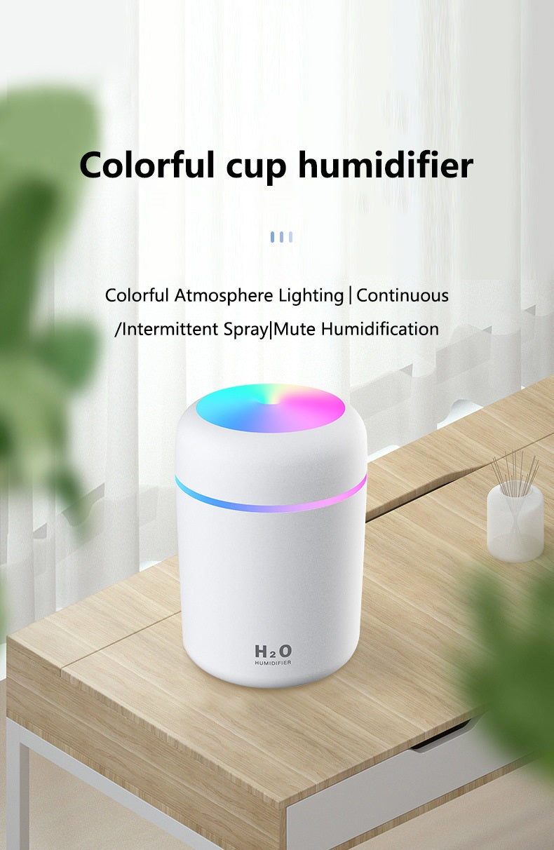 White Fitlybuy portable aroma humidifier with rainbow LED top light on a wooden desk.