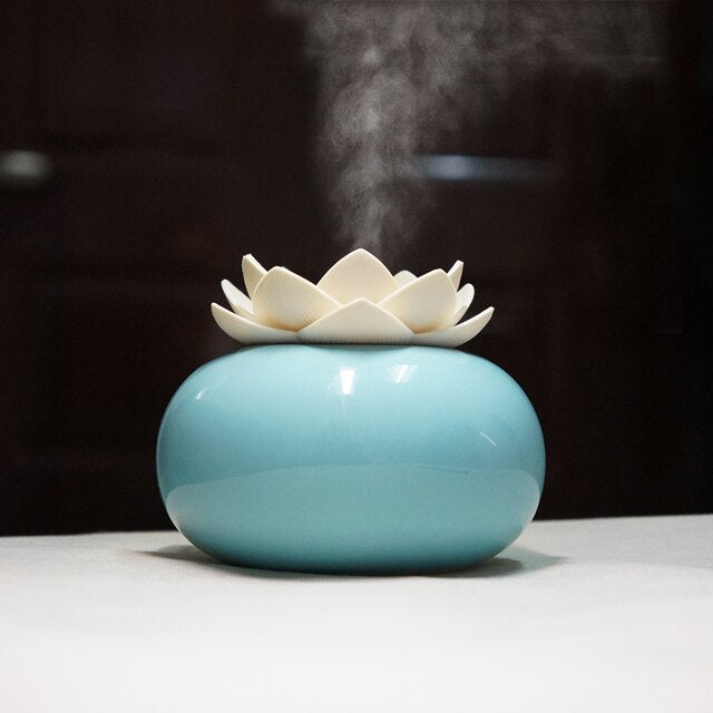 Blue ceramic Fitlybuy Lotus aroma humidifier with ultrasonic mist diffusing from the off-white lotus flower lid.