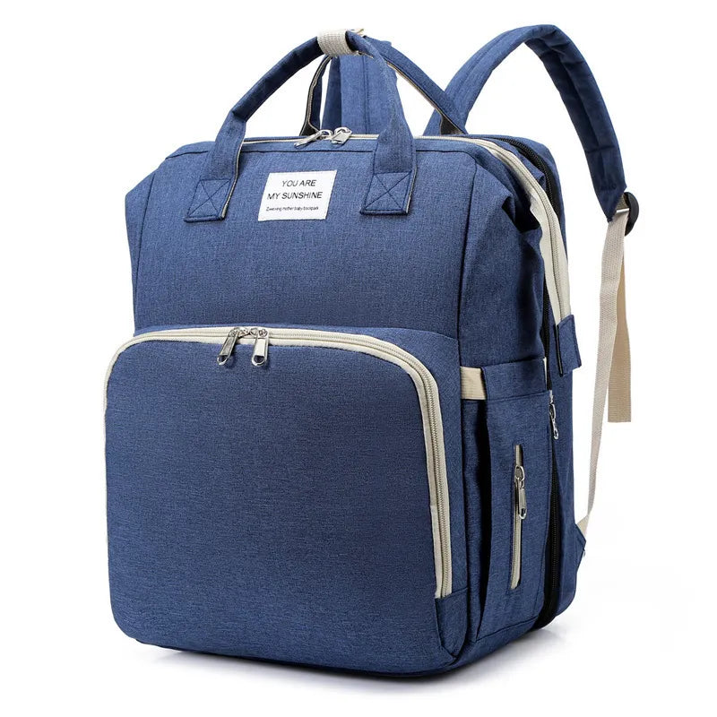 Blue waterproof Fitlybuy nappy backpack with USB port, top handles, and beige zippers on a plain white background.