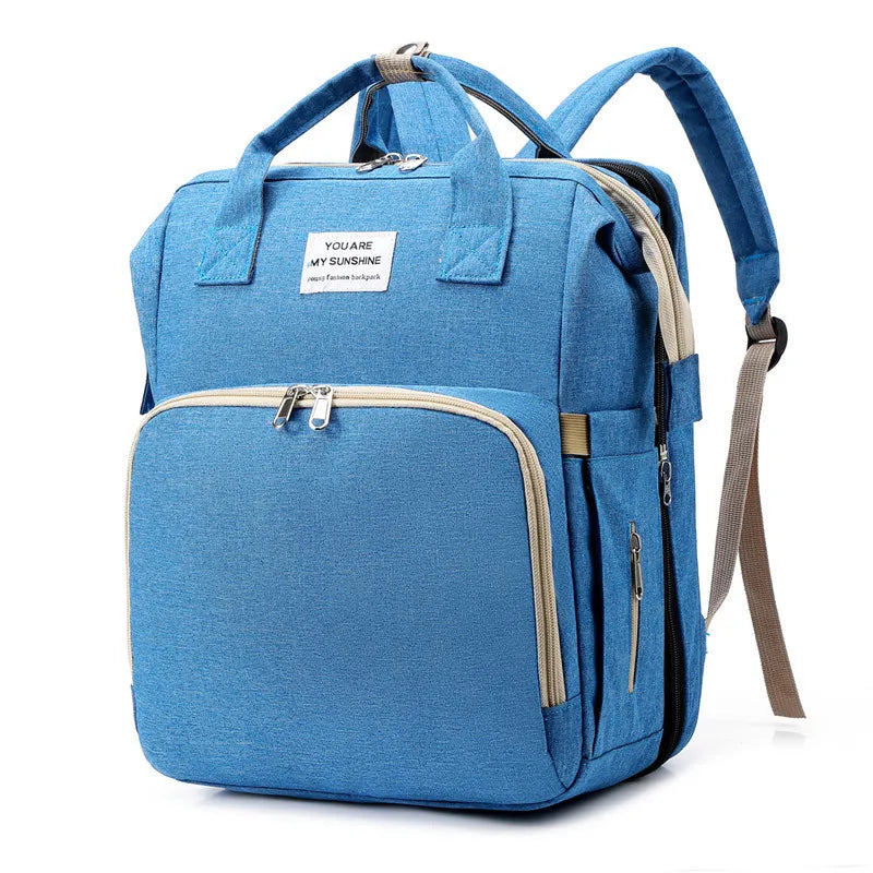 Blue waterproof mummy nappy backpack with USB charging, foldable bed design, and "You Are My Sunshine" label.