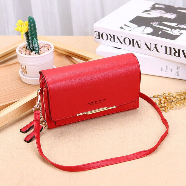 Red leather Fitlybuy crossbody bag with gold hardware, sitting on a wooden table next to a potted cactus and books.