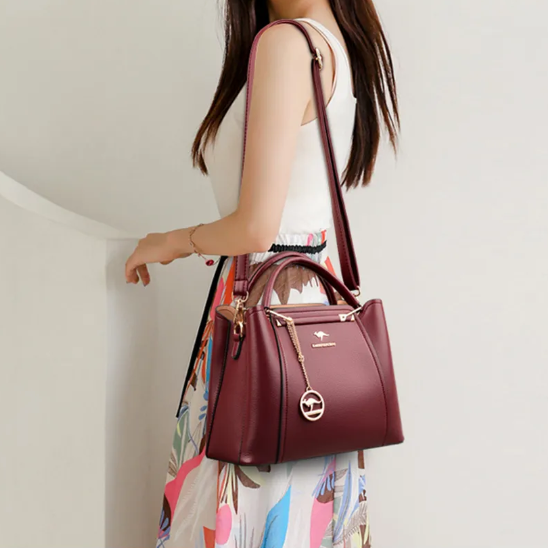 Woman wearing a maroon Fitlybuy luxury PU leather shoulder bag with a crossbody strap and gold kangaroo charm.