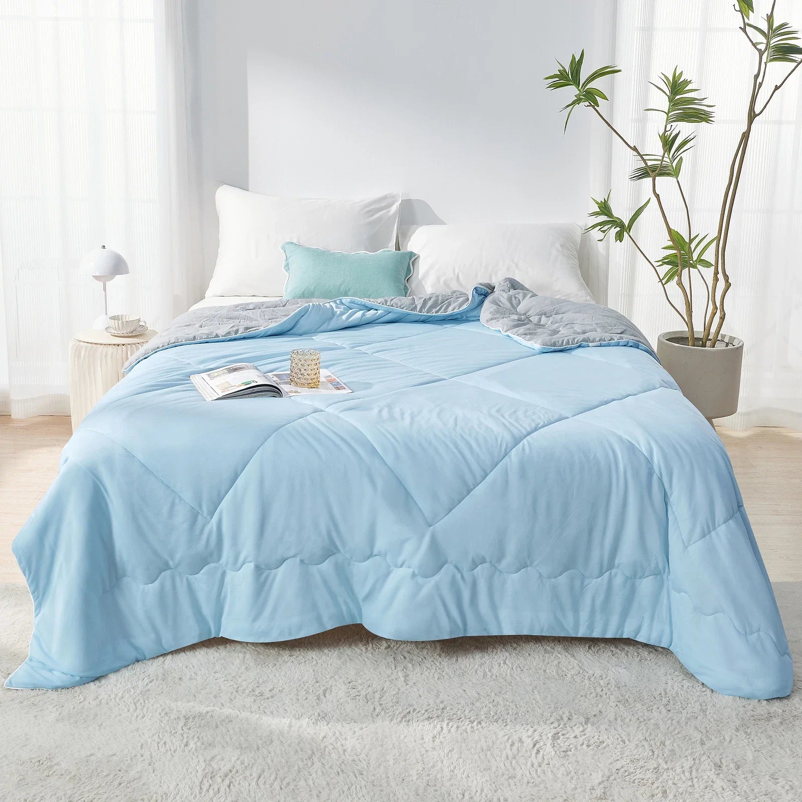 Fitlybuy Aussie Cool Ice quilt in light blue and grey ChillTech fabric, draped on a bed in a bright, modern bedroom.