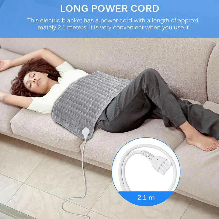 A woman rests on a sofa using a grey, quilted Fitlybuy heated therapy pad with a 2.1-meter long power cord.