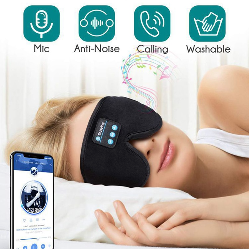 Black Fitlybuy DreamShield memory foam sleep mask with Bluetooth controls worn by a woman listening to music on a phone.